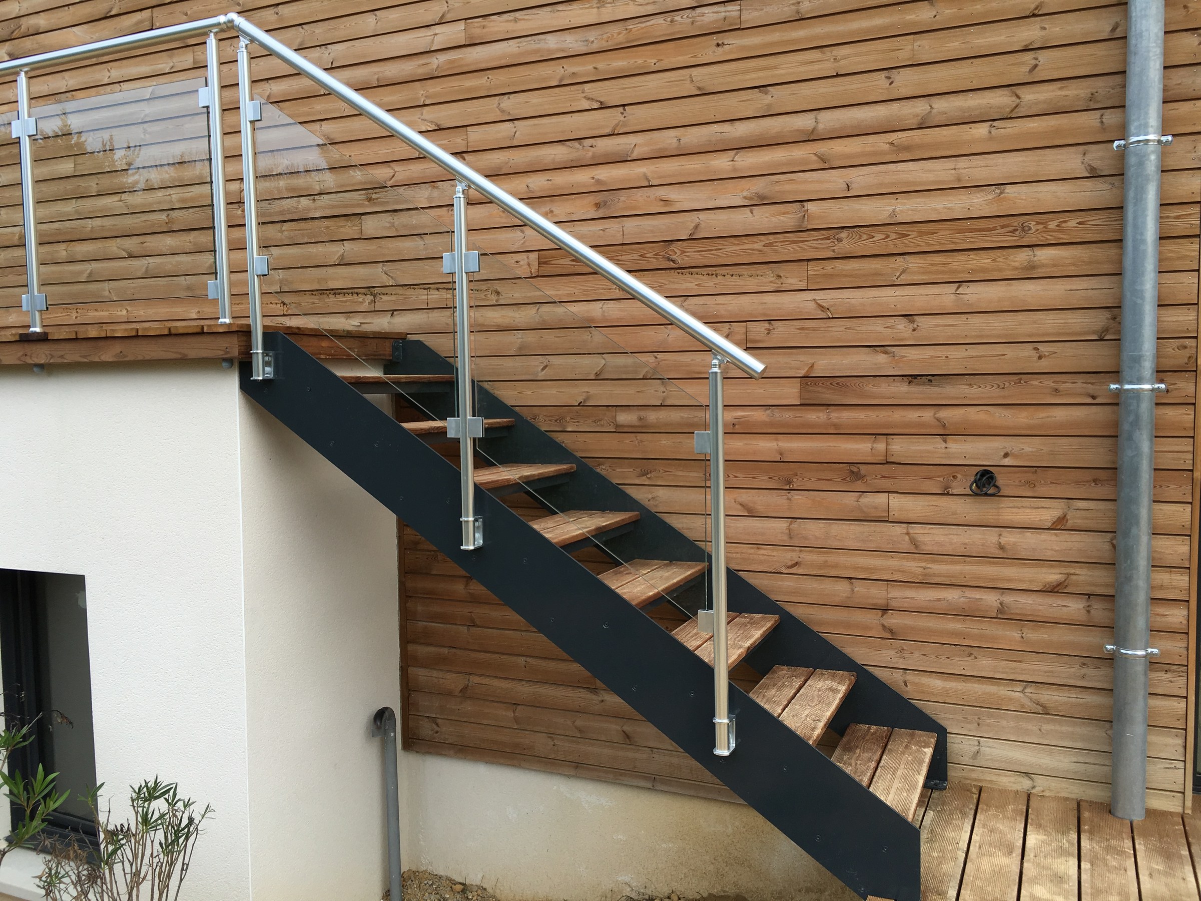 Escalier extérieur en bois avec limons et marches en pin traité menant à une terrasse de jardin